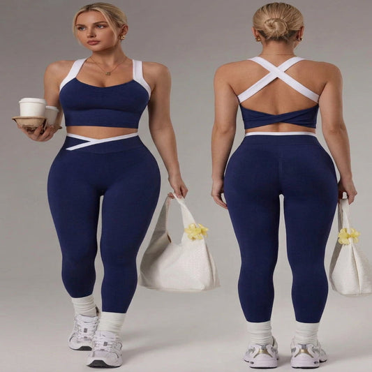 Two views of a woman modeling a navy blue and white athletic set consisting of a sports bra, long white sleeves, high-waisted leggings, and white socks, posed against a light gray studio background.