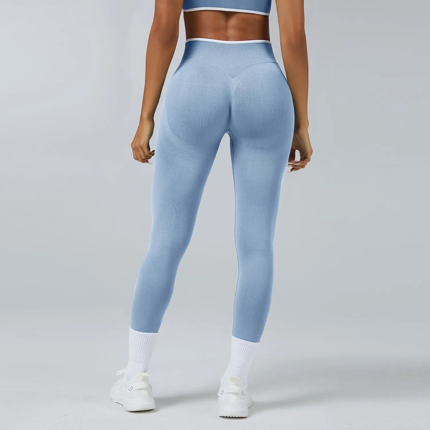 Person wearing light blue leggings on a gray background