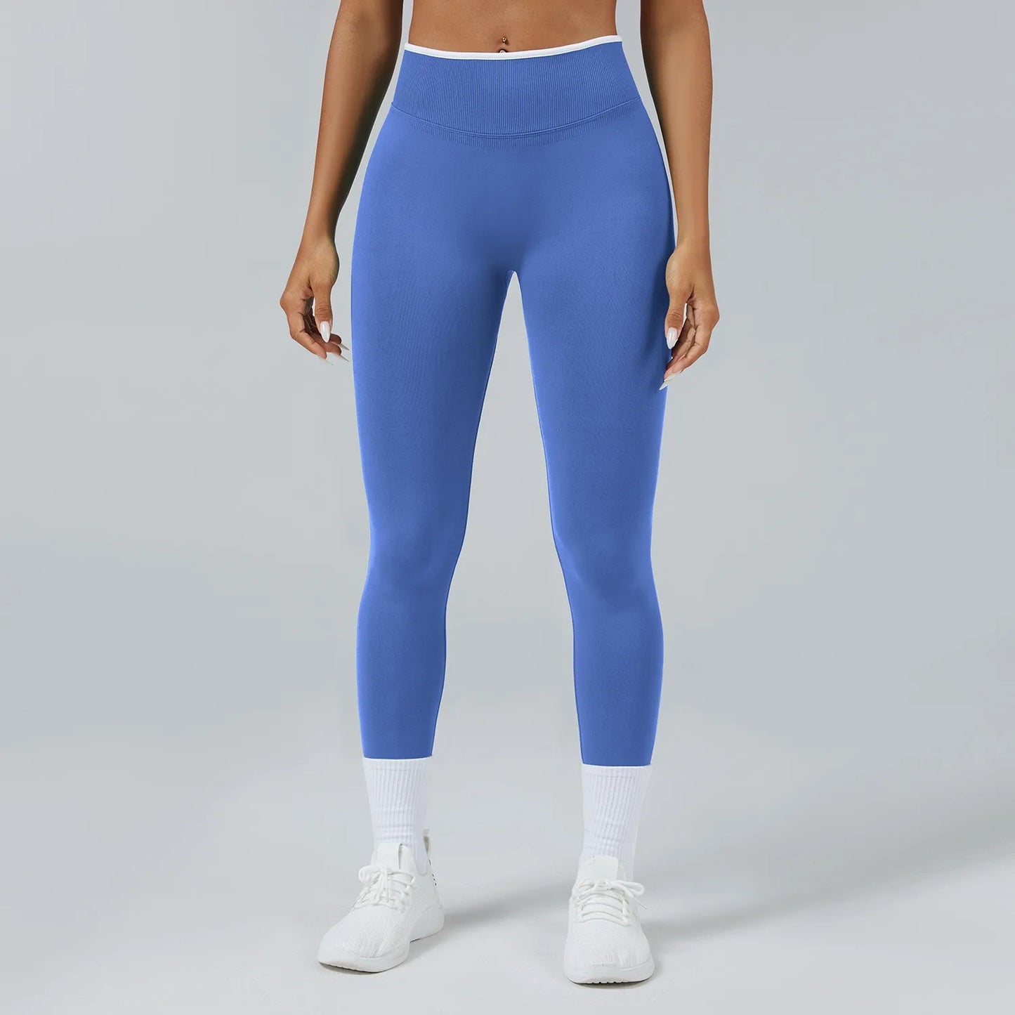 Person wearing blue leggings and white sneakers on a gray background
