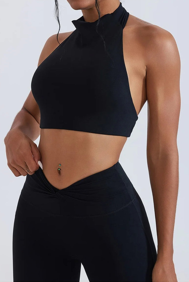 Person wearing a black halter top and leggings on a white background