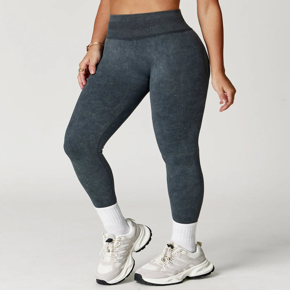 Person wearing dark gray leggings and white sneakers on a light gray background